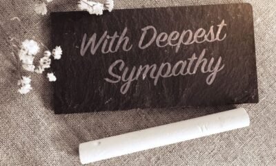 'With deepest sympathy' note with flowers on small chalk board⁠