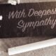 'With deepest sympathy' note with flowers on small chalk board⁠