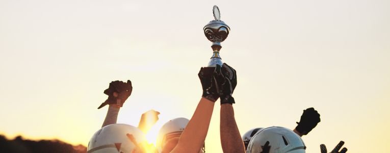 An American football team joyfully raising a championship trophy, celebrating their hard-earned victory on the field.