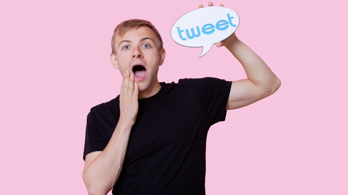 Portrait of surprised young man holding tweet bubble against pink background