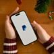 A female hand holding a smartphone with PayPal logo over table w