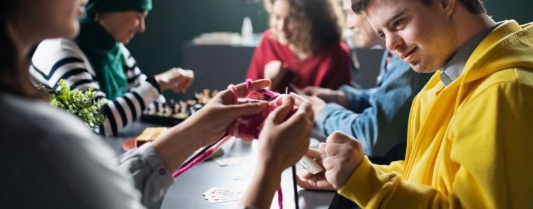 Group of People Playing Cards and Board Games in Community Center Inclusivity of Disabled Person