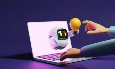 User hand touching cute robot light bulb through laptop on purple